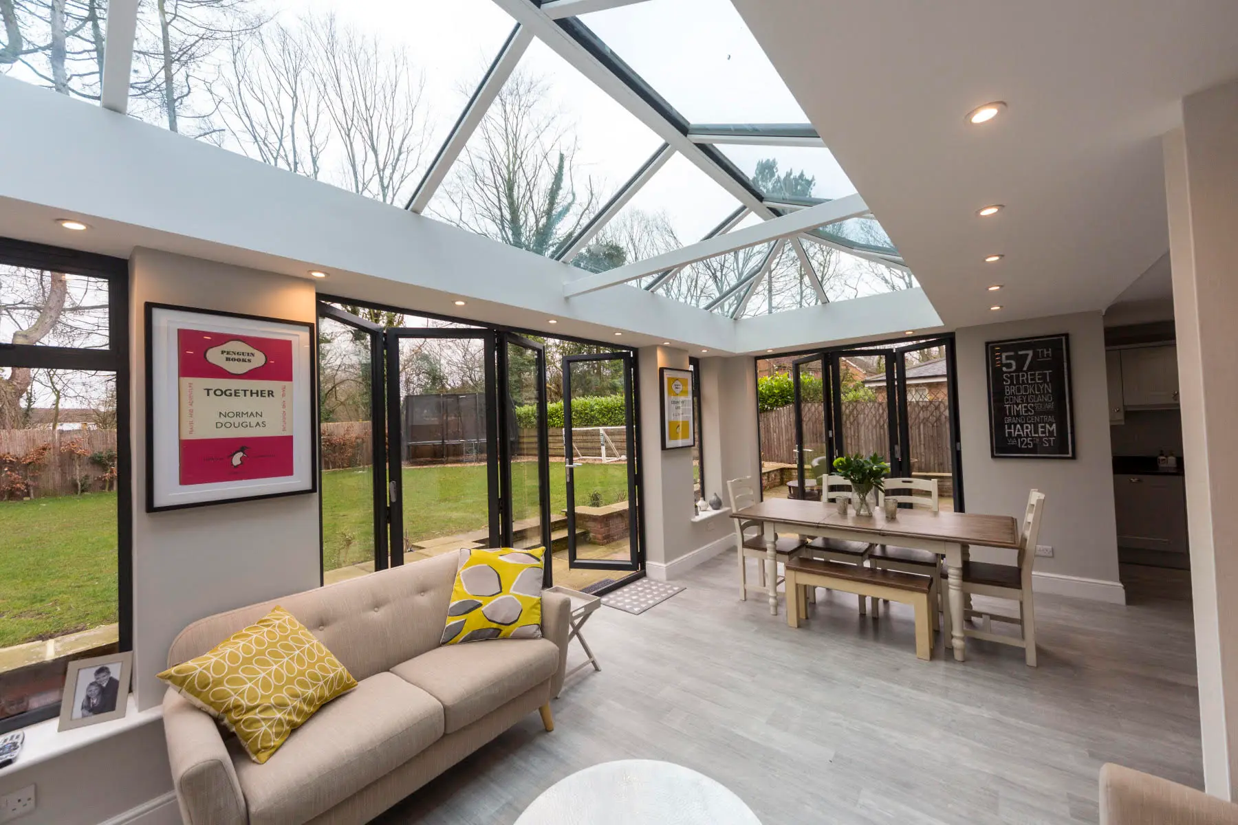 Modern sunroom with glass roof and dining area.